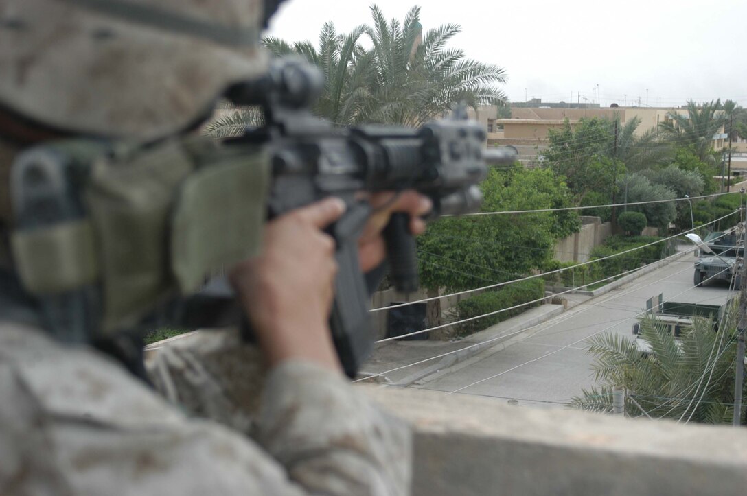 AR RAMADI, Iraq (April 13, 2005) - Lance Cpl. Chen Chen, a rifleman with 2nd Squad, 2nd Platoon, Company A, 1st Battalion, 5th Marine Regiment, aims his weapon from the rooftop of a building here and posts security for his fellow Marine with 2nd Platoon, Company A, 1st Battalion, 5th Marines, as they check out a potential improvised explosive device on the ground. The 19-year-old Los Angeles native originally from Beijing, and other Marines with 2nd Platoon, Company A, 1st Battalion, 5th Marines, conducted a combat patrol through the southern portion of the city where insurgents have actively been engaging coalition forces. Insurgents engaged the leathernecks in drive-by shooting midway through their combat patrol. Photo by Cpl. Tom Sloan