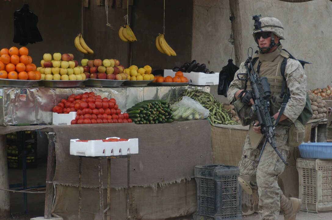 AR RAMADI, Iraq (April 13, 2005) - Lance Cpl. Justin L. Bystrom, a machine gunner with 1st Squad, 2nd Platoon, Company A, 1st Battalion, 5th Marine Regiment, walks past a street vendor with his weapon in hand during a patrol through a portion of the city here. The 18-year-old Parker Colo., native and other Marines with 2nd Platoon, Company A, 1st Battalion, 5th Marines, conducted a combat patrol through the southern portion of the city where insurgents have actively been engaging coalition forces. Insurgents engaged the leathernecks in drive-by shooting midway through their combat patrol. Photo by Cpl. Tom Sloan