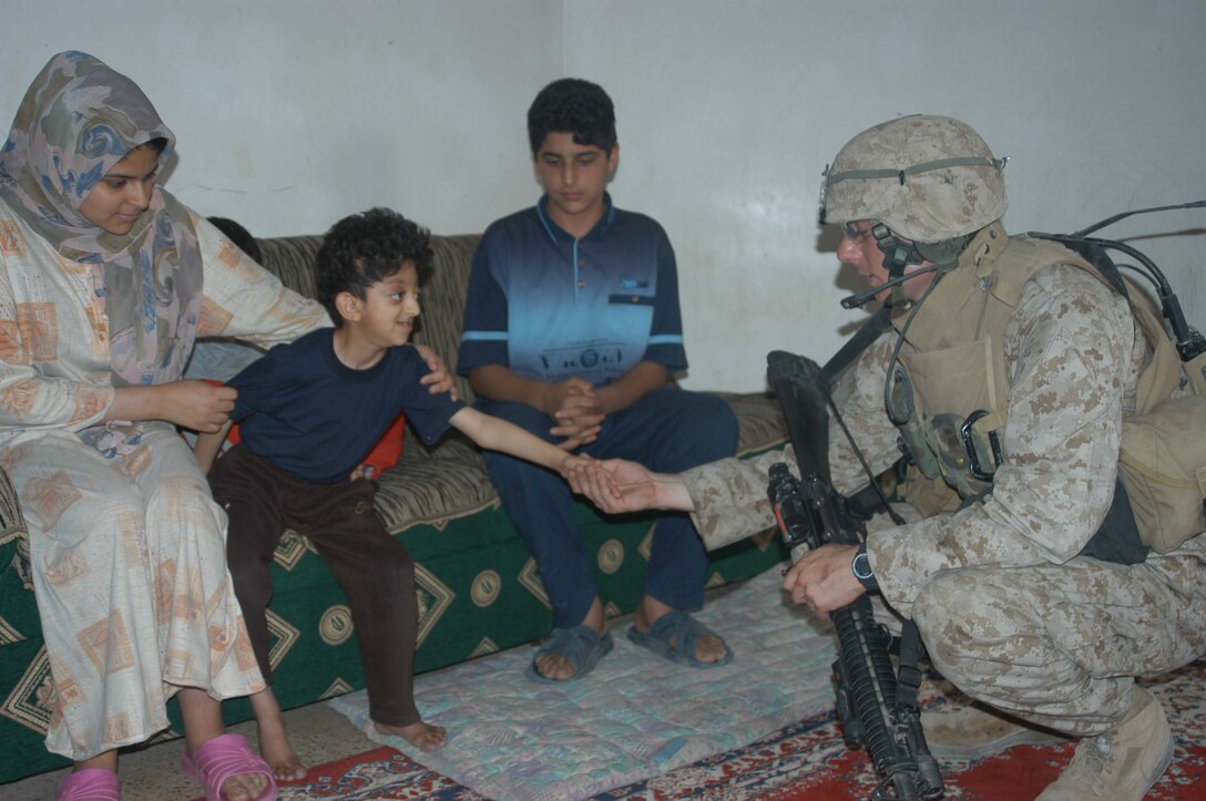 AR RAMADI, Iraq (April 13, 2005) - Cpl. Matt I. Bremer, squad leader for 2nd Squad, 2nd Platoon, Company A, 1st Battalion, 5th Marine Regiment, shakes hands with a smiling, young, Iraqi boy in his home here. The 22-year-old from Winston Salem, N.C., and other Marines 2nd Squad, 2nd Platoon, Company A, 1st Battalion, 5th Marines, were temporary guests in the boys home while they used the rooftop to set up an over watch. Marines with 2nd Platoon, Company A, 1st Battalion, 5th Marines, conducted a combat patrol through the southern portion of the city where insurgents have actively been engaging coalition forces. Insurgents engaged the leathernecks in drive-by shooting midway through their combat patrol. Photo by Cpl. Tom Sloan