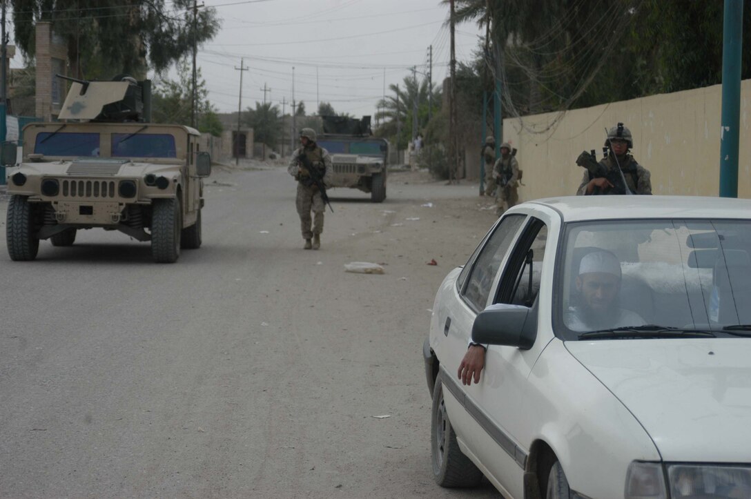 AR RAMADI, Iraq (April 13, 2005) - An Iraqi man sits quietly in his car on a street here as Marines with 2nd Platoon, Company A, 1st Battalion, 5th Marine Regiment, approach him from behind during a patrol. Marines with 2nd Platoon, Company A, 1st Battalion, 5th Marines, conducted a combat patrol through the southern portion of the city where insurgents have actively been engaging coalition forces. Insurgents engaged the leathernecks in drive-by shooting midway through their combat patrol. Photo by Cpl. Tom Sloan