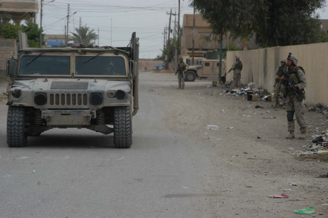 AR RAMADI, Iraq (April 13, 2005) - Marines with 2nd Platoon, Company A, 1st Battalion, 5th Marine Regiment, are escorted by Humvees as walk down a street here during a patrol. Marines with 2nd Platoon, Company A, 1st Battalion, 5th Marines, conducted a combat patrol through the southern portion of the city where insurgents have actively been engaging coalition forces. Insurgents engaged the leathernecks in drive-by shooting midway through their combat patrol. Photo by Cpl. Tom Sloan