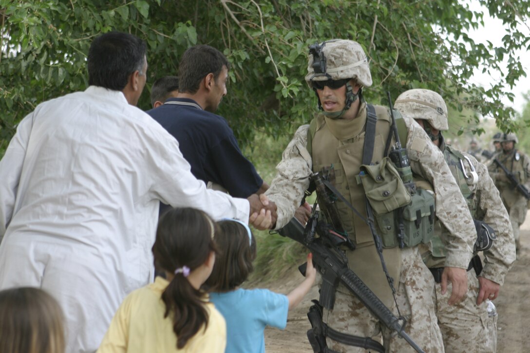 SAQLAWIYAH, Iraq - Maj. Chris E. Phelps, 1st Battalion, 6th Marine Regiment's civil affairs team leader, shakes hands with some local farmers while patrolling alongside Company A, 1st Battalion, 6th Marine Regiment personnel here.  Civil affairs Marines are conducting assessments on the community here to determine what utilities and services the local population needs.