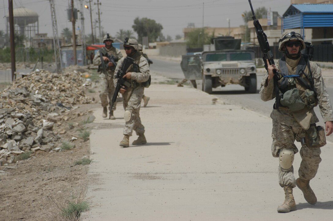 AR RAMADI, Iraq (May 13, 2005) - Lance Cpl. Justin R. Corry, an assault man with 2nd Squad, 2nd Platoon, Company B, 1st Battalion, 5th Marine Regiment, and two other Marines in his squad patrol along side a main street in the city here. The 19-year-old Jackson, Mich., native and his fellow 2nd Platoon warriors conducted a three-hour presence patrol through a portion of their company's area of operations notorious for insurgent activity. The Marines encountered sporadic machine gun fire from insurgents during their mission, which was geared toward disrupting enemy activity. The Marines accomplished their mission and returned to their firm base, Camp Ramadi, safely. Photo By: Cpl. Tom Sloan