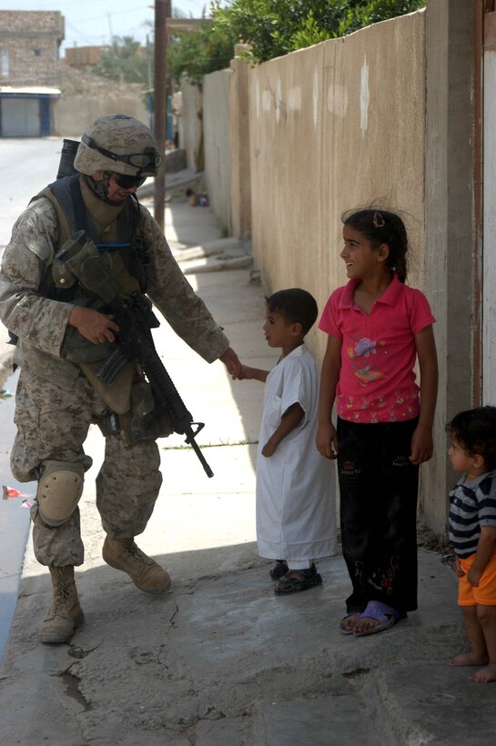 AR RAMADI, Iraq (May 13, 2005) - During a patrol through the city here, Lance Cpl. Justin R. Corry, an assault man with 2nd Squad, 2nd Platoon, Company B, 1st Battalion, 5th Marine Regiment, shakes hands with a young, Iraqi boy standing on a street corner. The 19-year-old Jackson, Mich., native and his fellow 2nd Platoon warriors conducted a three-hour presence patrol through a portion of their company's area of operations notorious for insurgent activity. The Marines encountered sporadic machine gun fire from insurgents during their mission, which was geared toward disrupting enemy activity. The Marines accomplished their mission and returned to their firm base, Camp Ramadi, safely. Photo By: Cpl. Tom Sloan