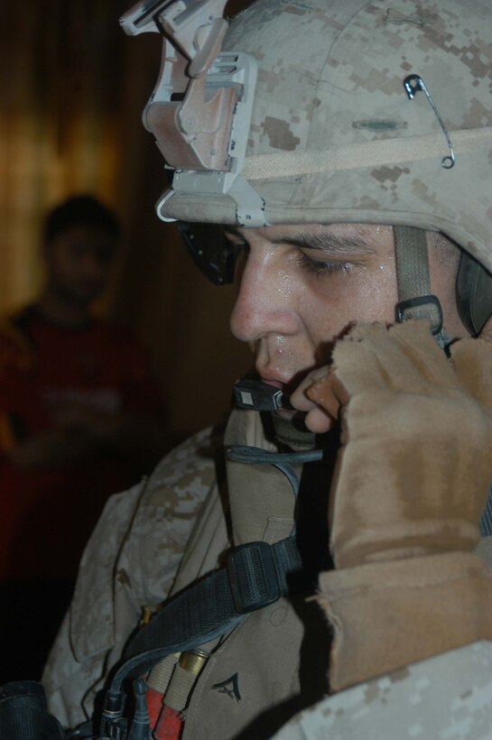 AR RAMADI, Iraq (May 13, 2005) - Sweat pouring from his brow, Lance Cpl. Aaron R. Martinez, a 21-year-old Lubbock, Texas, native and team leader with 2nd Squad, with 2nd Platoon, Company B, 1st Battalion, 5th Marine Regiment, communicates with his squad members on the rooftop of a house here during a patrol. The 2001 Robertson High School graduate and his fellow 2nd Platoon warriors conducted a three-hour presence patrol through a portion of their company's area of operations notorious for insurgent activity. The Marines encountered sporadic machine gun fire from insurgents during their mission, which was geared toward disrupting enemy activity. The Marines accomplished their mission and returned to their firm base, Camp Ramadi, safely. Photo By: Cpl. Tom Sloan