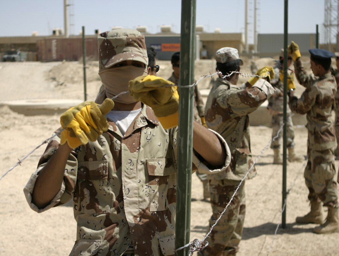 FALLUJAH, Iraq - Iraqi soldiers tie strands of barbed wire here June 13 as they put up a cattle fence.  Engineers with 2nd Platoon, Company A, 2nd Combat Engineer Battalion instructed the soldiers on how to string various types of wires, board up windows and fortify defensive positions.