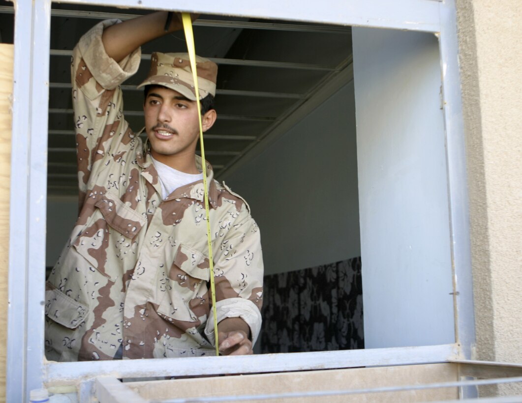 FALLUJAH, Iraq - An Iraqi soldier measures a window frame inside a building here June 13 while preparing to board up the opening with wood and sandbags.  Marine engineers with 2nd Platoon, Company A, 2nd Combat Engineer Battalion instructed the soldiers on how to string various types of wires, board up windows and fortify defensive positions.