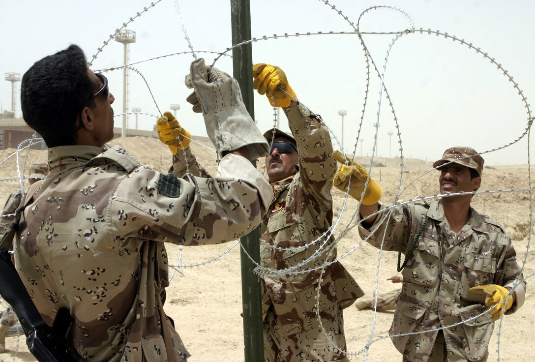 FALLUJAH, Iraq - Iraqi soldiers thread a strand of concertina wire onto an engineer stake here June 13.  Marine engineers with 2nd Platoon, Company A, 2nd Combat Engineer Battalion instructed the soldiers on how to string various types of wires, board up windows and fortify defensive positions.