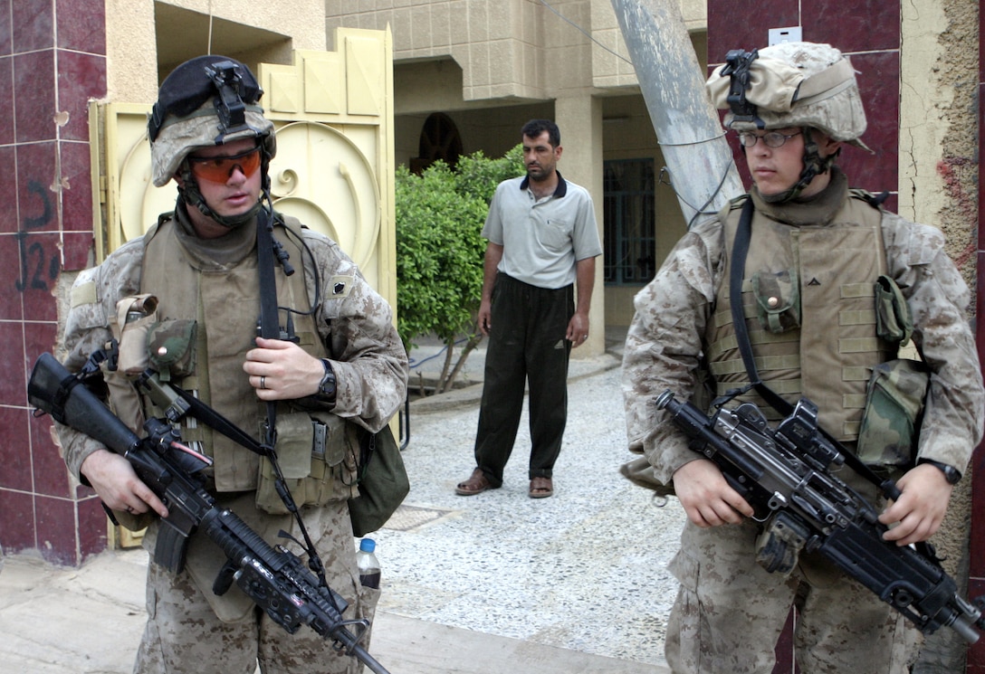 FALLUJAH, Iraq - Cpl. Adam Decrane, a team leader with 1st Squad, 1st Platoon, Company C, 1st Battalion, 6th Marine Regiment, left, provides security outside a home here Aug. 13 beside one of his team members during Operation Hard Knock.   The 25-year-old Abingdon, Ill. native, fellow Marines, and Iraqi Security Forces blocked off a sector of Northwestern Fallujah to search dozens of houses for weapons and to gather census information on the populace.