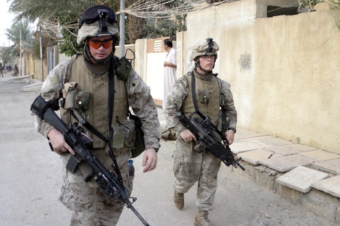 FALLUJAH, Iraq - Cpl. Adam Decrane, a team leader with 1st Squad, 1st Platoon, Company C, 1st Battalion, 6th Marine Regiment, left, patrols down a street here Aug. 13 beside one of his team members during Operation Hard Knock.   The 25-year-old Abingdon, Ill. native, fellow Marines, and Iraqi Security Forces blocked off a sector of Northwestern Fallujah to search dozens of houses for weapons and to gather census information on the populace.