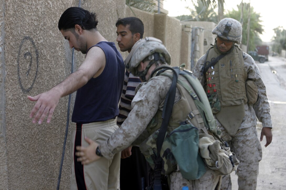 FALLUJAH, Iraq - Personnel with Company C, 1st Battalion, 6th Marine Regiment guard and search two suspected insurgent supporters they detained here Aug. 13 during Operation Hard Knock.  The battalion's Marines and Iraqi Security Forces blocked off a sector of Northwestern Fallujah to search dozens of houses for weapons and to gather census information on the populace.