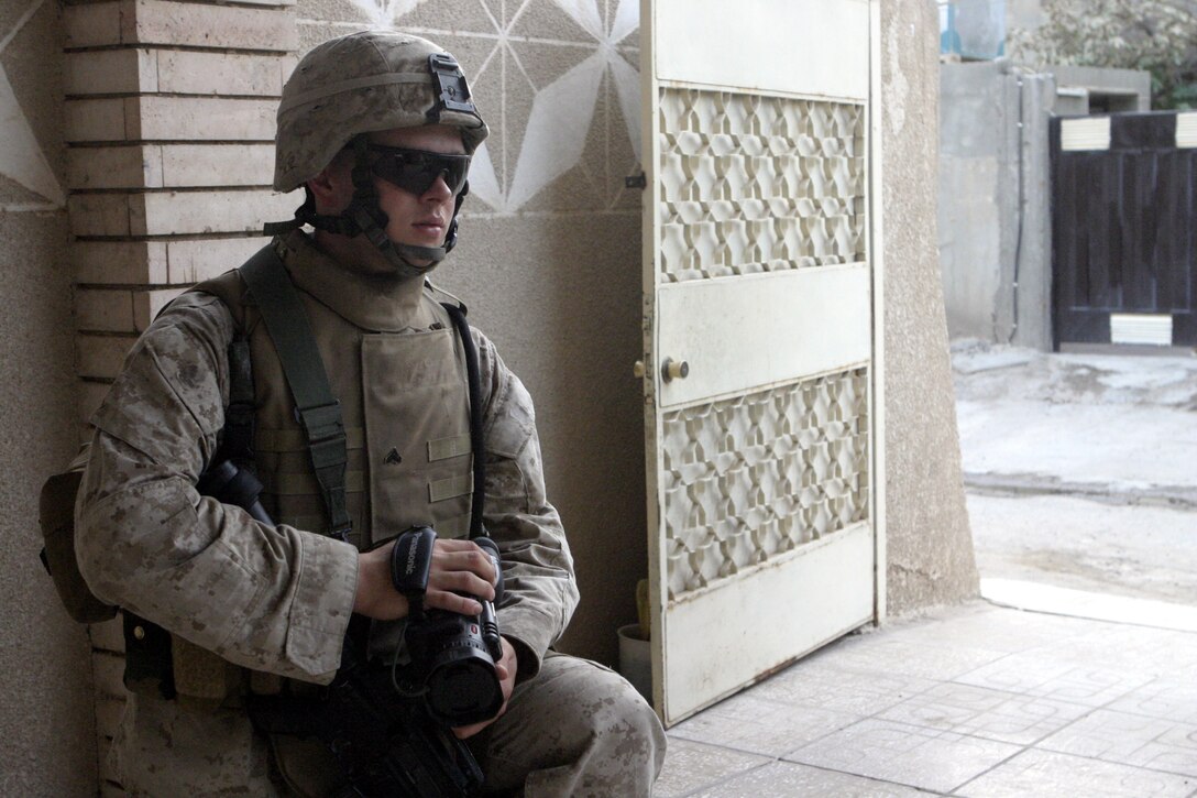 FALLUJAH, Iraq - Cpl Thomas Rodman, video combat cameraman with 1st Battalion, 6th Marine Regiment, lowers his video camera during a patrol here Aug. 13 and prepares to take the next shot.  The 20-year-old Crowley, La. native works alongside a photographer to document the daily lives, operations and hardships of their fellow Marines here.