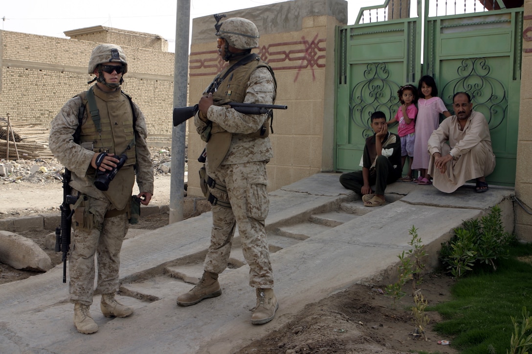 FALLUJAH, Iraq - Cpl Thomas Rodman, video combat cameraman with 1st Battalion, 6th Marine Regiment, stands prepared to film next to a Navy corpsman while on patrol here Aug. 13.  The 20-year-old Crowley, La. native works alongside a photographer to document the daily lives, operations and hardships of their fellow Marines here.