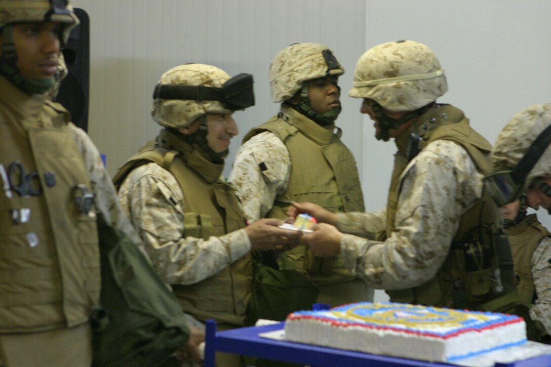 CAMP BLUE DIAMOND, AR RAMADI, Iraq - Colonel David K. Hough, the commanding Officer of Headquarters Battalion, 2nd Marine Division, presents the first piece of the traditional birthday cake to Cmdr. Robert Puder, the oldest sailor present Oct. 13 during a ceremony for the 230th birthday of the Navy. Service members with the 2nd Marine Division celebrated the Navy's birthday with a traditional cake cutting ceremony.