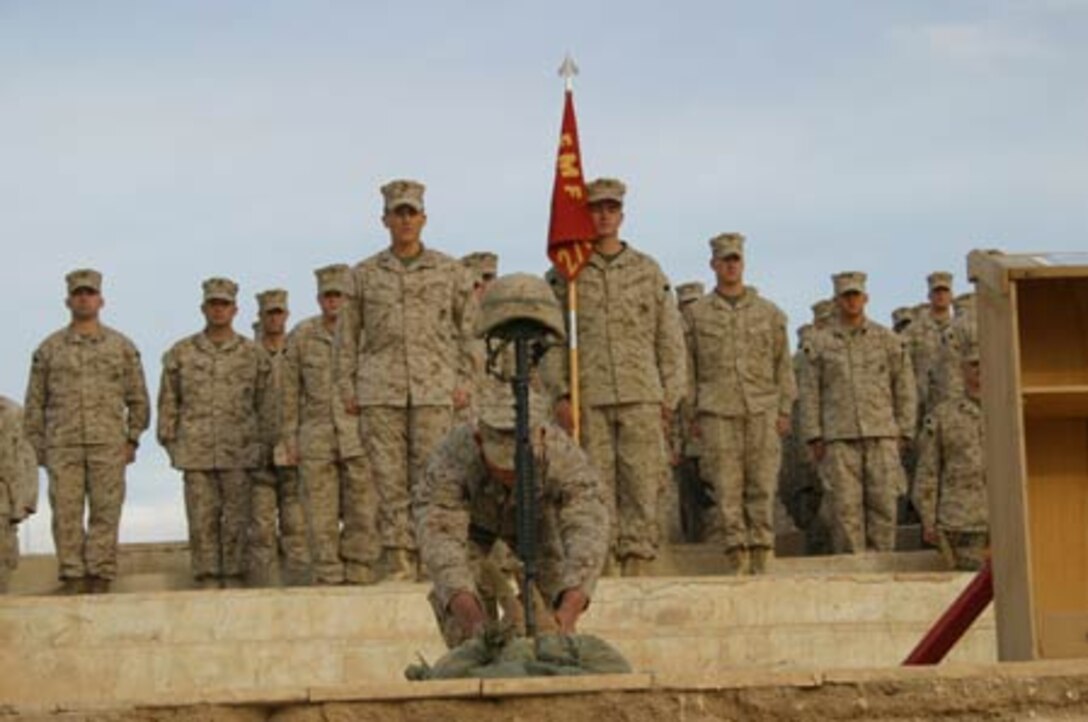 A Marine from Weapons Company, 2nd Battalion, 6th Marines places a pair of boots at a memorial for one of his fallen brothers-in-arms, Cpl. William G. Taylor, a 26-year-old Kansas City, Mo. native, who was killed in action Nov. 30, 2005 by anti-coalition forces while deployed with the battalion.