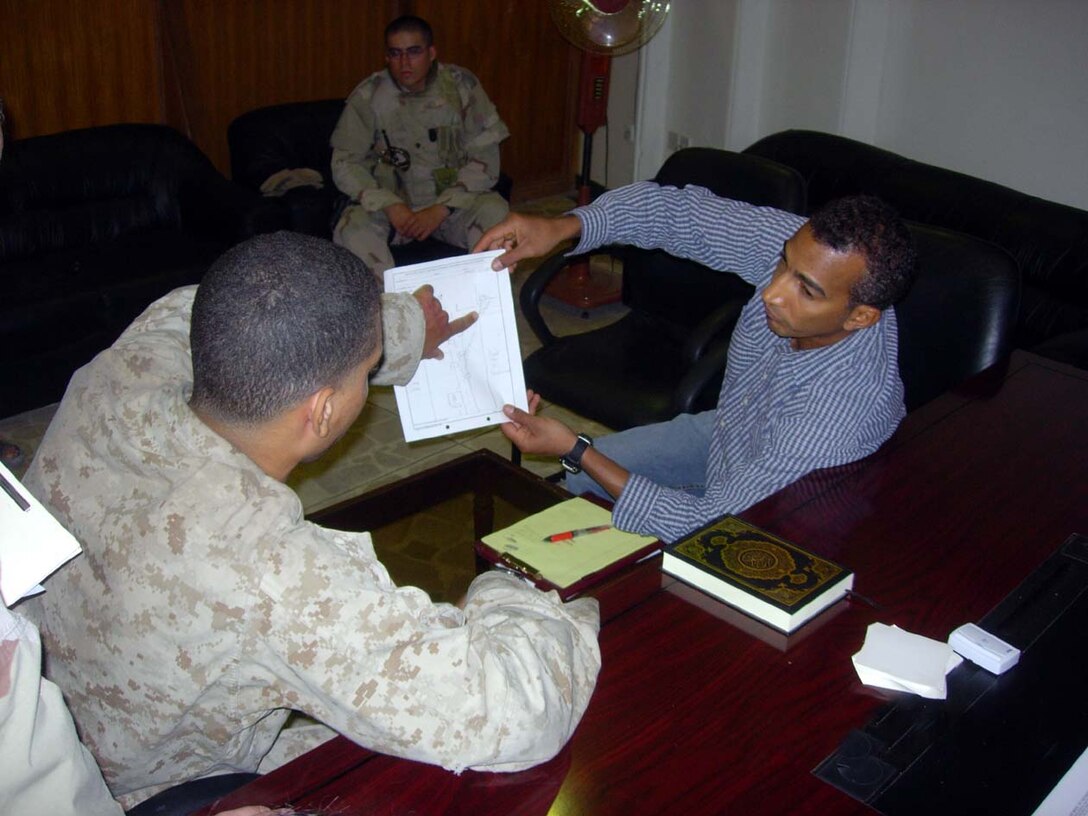 Baghdad, Iraq -- A Marine explains through a translator, part of the evidence for the case against the detainee he and his company had taken in earlier in the deployment here.  Photo Courtesy of Capt. Carlos Davila.