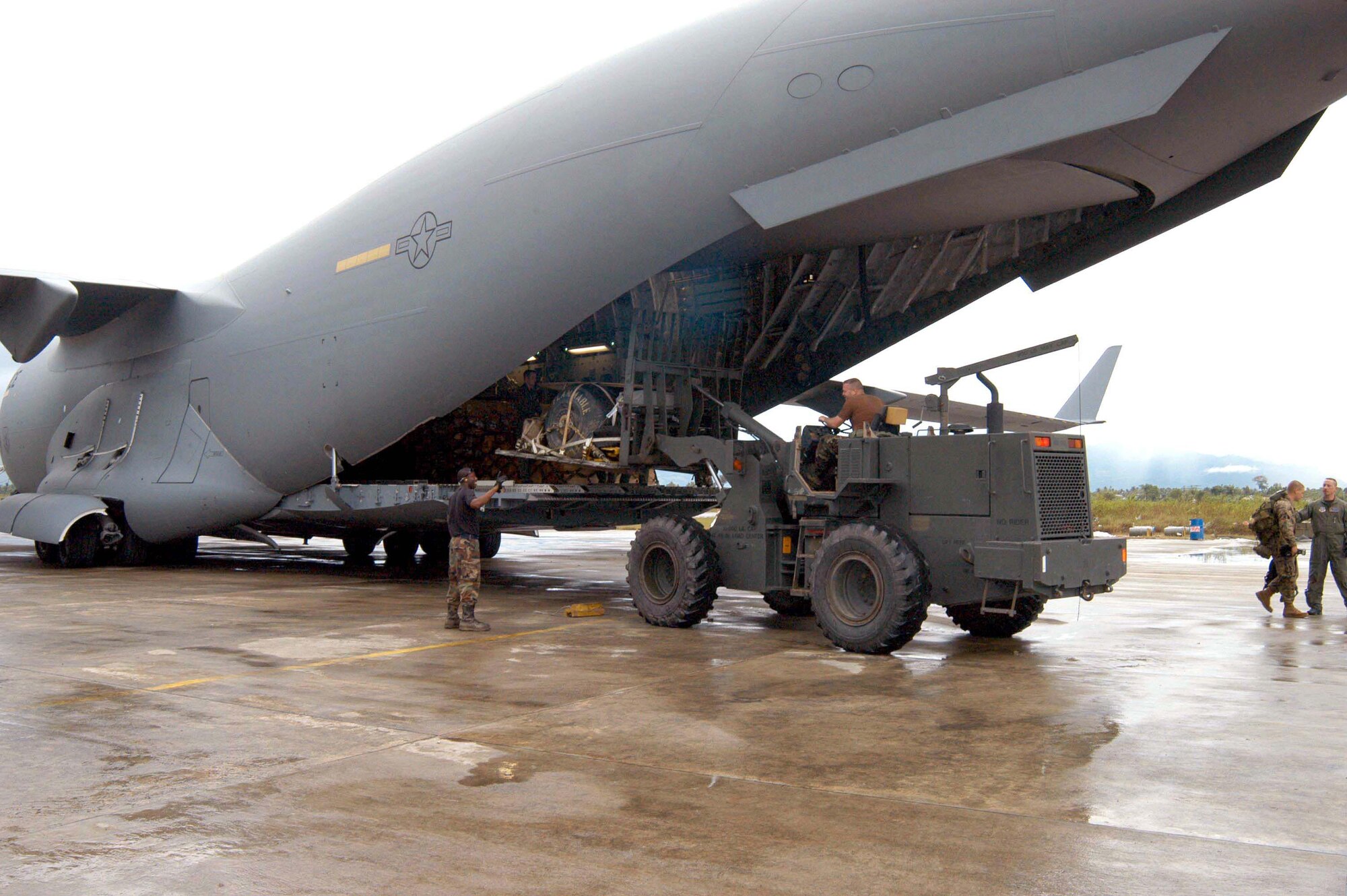 BANDA ACEH, Indonesia (AFPN) -- A tanker airlift control element team uses an all- terrain forklift to unload pallets of cargo from a C-17 Globemaster III that flew here from Utapao, Thailand.  The C-17 was flown by a crew from the 8th Airlift Squadron based at McChord Air Force Base, Wash. (U.S. Air Force photo by Samantha L. Quigley)