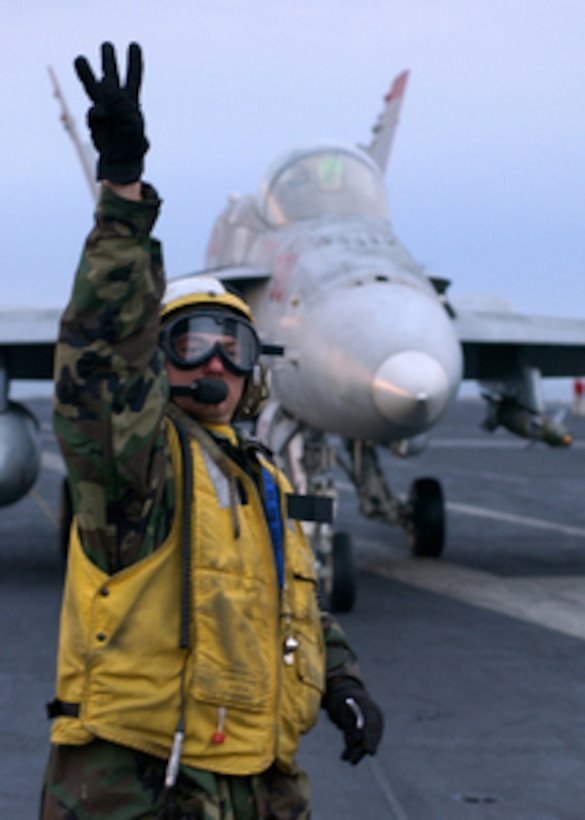 Petty Officer 3rd Class Jason Baty relays a signal to other flight deck crew of the aircraft carrier USS Harry S. Truman (CVN 75) as an F/A-18C Hornet taxis towards the catapult for launch on Dec. 24, 2004. Truman and its embarked Carrier Air Wing 3 is providing close air support and conducting intelligence, surveillance, and reconnaissance missions over Iraq. Baty is a Navy Aviation Boatswain's Mate (Aircraft Handler). The Hornet is assigned to Strike Fighter Squadron 37. 