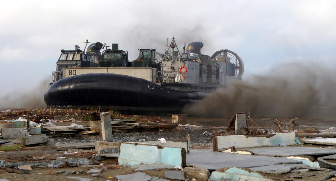 A Landing Craft Air Cushioned filled with humanitarian aid supplies from the 15th Marine Expeditionary Unit (Special Operations Capable) kicks up some sand as it lands on the beach. After the supplies were unloaded off of the LCAC, Marines and sailors delivered them to a local refugee camp.