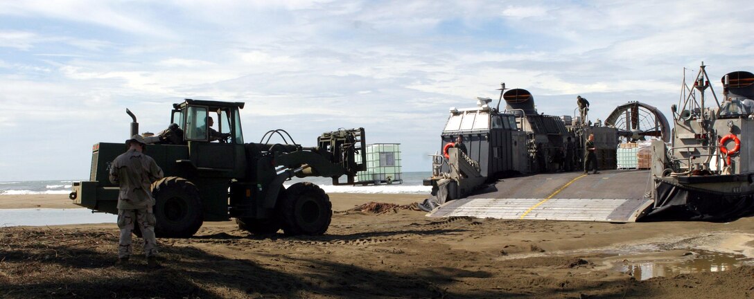 A forklift unloads humanitarian aid supplies from a Landing Craft Air Cushioned with the 15th Marine Expeditionary Unit (Special Operations Capable). After the supplies were unloaded off of the LCAC, Marines and sailors delivered them to a local refugee camp.