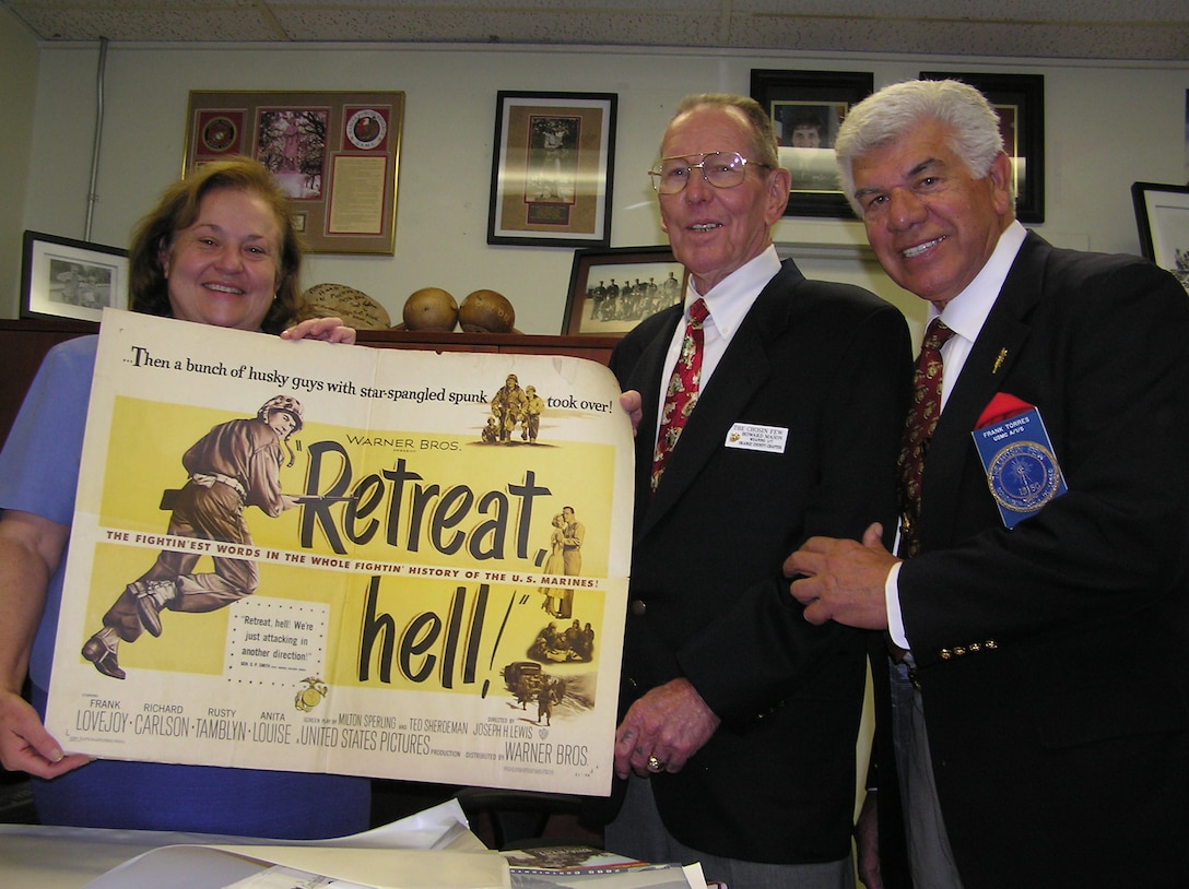 Faye Jonason, the history and museums officer for the Consolidated Public Affairs Office, Howard Mason and Frank Torres, both Korean War veterans and members of the Colonel William E. Barber Chosin Few Chapter of Orange County, pose Oct. 13 at the Scout Newspaper office with a poster of the 1952 Warner Bros. movie ?Retreat Hell.? Mason and Torres are among some 3000 members of the Chosin Few organization, which is a brotherhood dedicated to paying homage to the men who fought and fell on the "Frozen Chosin" battlefield along with honoring those who survived. The Chosin Few has 50 chapters nationwide. The Colonel William E. Barber chapter held its annual Inchon Landing Commemorative Luncheon at Sharkey's Hotel on Del Mar Beach here Sept. 17.