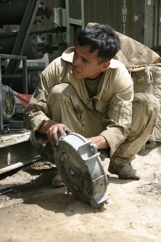 CAMP BAHARIA, Iraq - Lance Cpl. Peter Ayala, hygiene equipment operator with 8th Engineer Support Battalion, II Marine Expeditionary Force and Laredo, Texas native, looks up from fixing a component of a Reverse Osmosis Water Purification Unit here May 1.  Ayala and his teammates are responsible for providing several military camps in the area with water by pumping and purifying tens of thousands of gallons everyday from the manmade lake here.