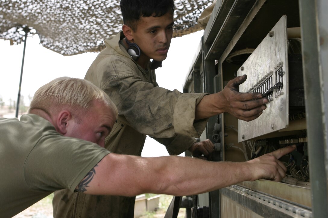 CAMP BAHARIA, Iraq - Sgt. Wesley Webb, hygiene equipment operator with 8th Engineer Support Battalion, II Marine Expeditionary Force and Hinton, Iowa native, front, and Lance Cpl. Peter Ayala, a fellow hygiene equipment operator, back, adjust a Reverse Osmosis Water Purification Unit's settings here May 1.  The Marines are responsible for providing several military camps in the area with water by pumping and purifying tens of thousands of gallons everyday from the manmade lake here.