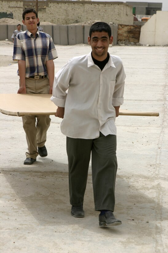 FALLUJAH, Iraq - Two Iraqi high school students carry a newly donated chalkboard into their school here May 2.  Iraqi Security Forces and Marines here visited local schools to distribute blackboards, school desks, and writing supplies as part of the ongoing joint civil-military mission, "Operation Blackboard."