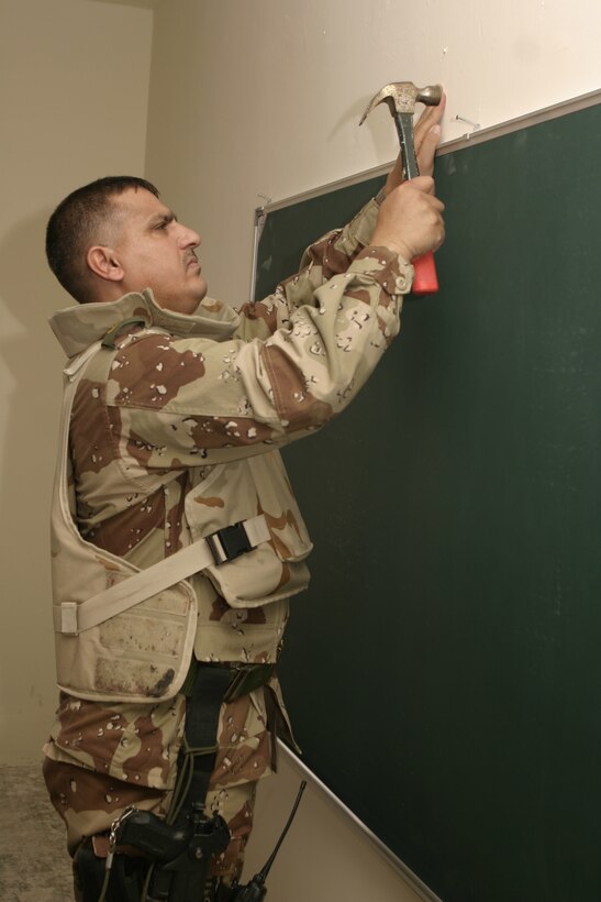FALLUJAH, Iraq - Iraqi Maj. Muhammad-Hasan Hasan Fuaad, executive officer for 1st Battalion, 2nd Brigade, Iraqi Security Forces, hangs up a new blackboard inside a school classroom here May 2.  Iraqi Security Forces and Marines here visited local schools to distribute blackboards, school desks, and writing supplies as part of the ongoing joint civil-military mission, "Operation Blackboard."