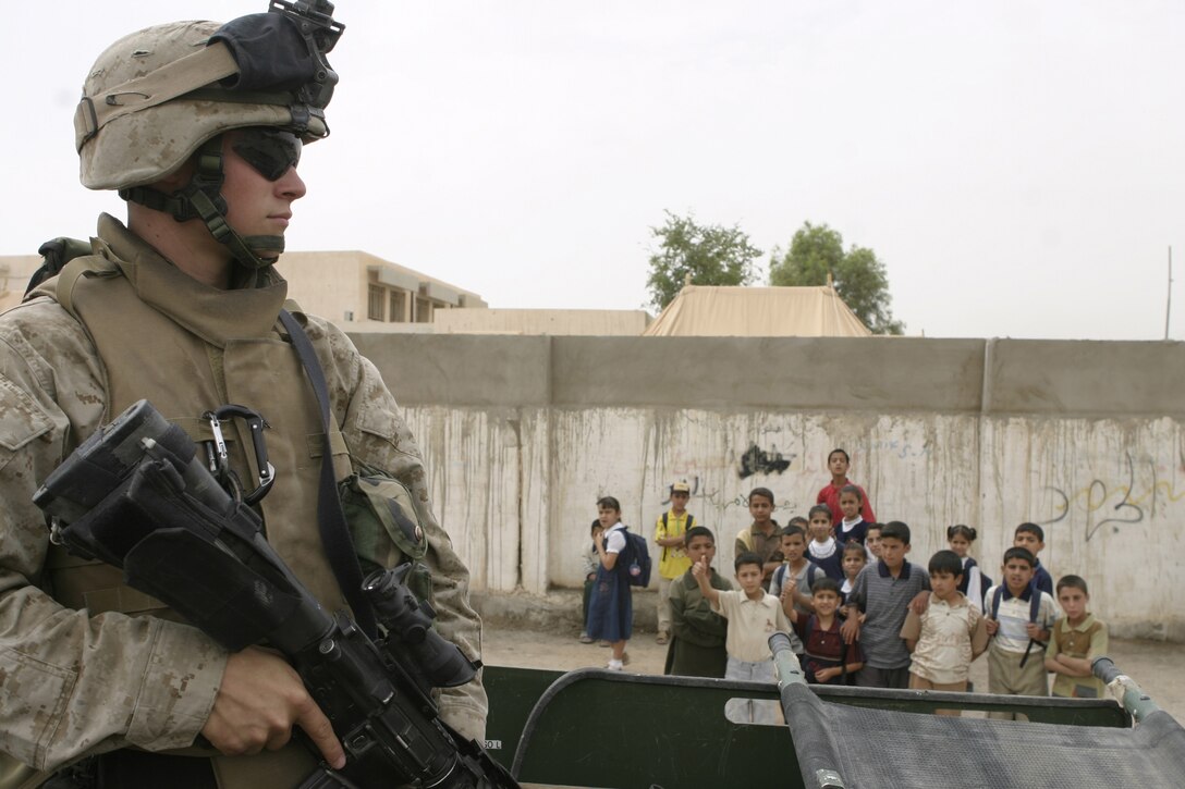 FALLUJAH, Iraq - Cpl. Dan Plane, a machine gunner with Company B, 1st Battalion, 6th Marine Regiment and Boone, N.C. native, provides security atop a military vehicle outside a school here May 2.  Iraqi Security Forces and Marines here visited local schools to distribute blackboards, school desks, and writing supplies as part of the ongoing joint civil-military mission, "Operation Blackboard."