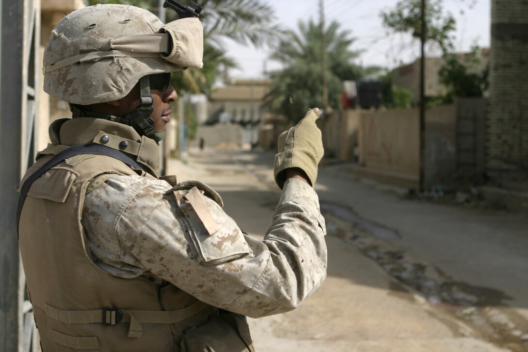 FALLUJAH, Iraq - A Marine with Company B, 1st Battalion, 6th Marine Regiment directs fellow Marines as they provide security outside a school here May 4, while other personnel and Iraqi soldiers distribute chalkboards inside.  Iraqi Security Forces and Marines here visited local schools to distribute blackboards, school desks, and writing supplies as part of the ongoing joint civil-military mission, "Operation Blackboard."