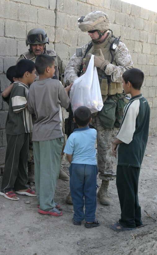 FALLUJAH, Iraq - Gunnery Sgt. William Clare, Company B, 1st Battalion, 6th Marine Regiment's company gunnery sergeant, and an Iraqi soldier hand out candy to children outside a local school May 4, while other personnel and soldiers distribute chalkboards inside.  Iraqi Security Forces and Marines here visited local schools to distribute blackboards, school desks, and writing supplies as part of the ongoing joint civil-military mission, "Operation Blackboard."