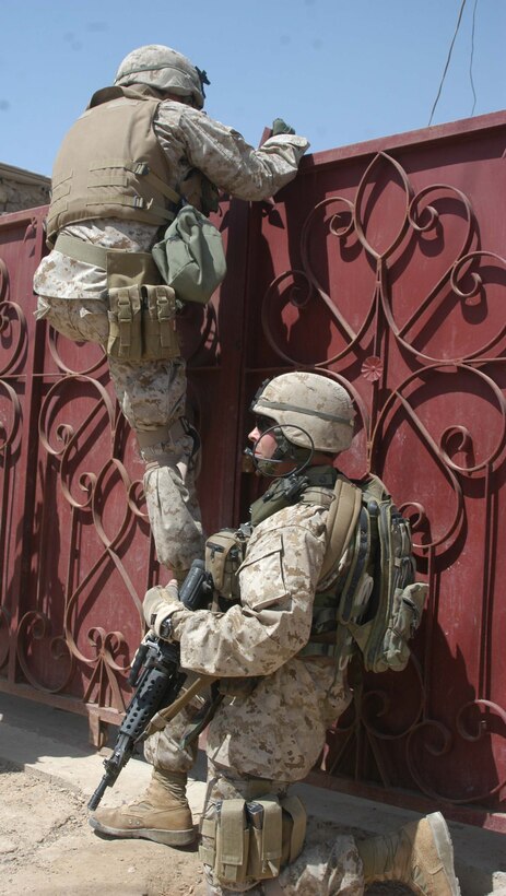 AR RAMADI Iraq (June 14, 2005) - Sergeant Michael A. Burgess, an assault man with 1st Section, 1st Mobile Assault Platoon, Company W, 1st Battalion, 5th Marine Regiment, helps his comrade, Sgt. Tim R. Cyparski, over a locked gate during a mission here. Insurgents attacked the 28-year-old from Willoughby, Ohio, and his fellow Marines with an improvised explosive device during a presence patrol they executed in the southern portion of the city. No one was hurt and no vehicles were damaged. Photo by: Cpl. Tom Sloan