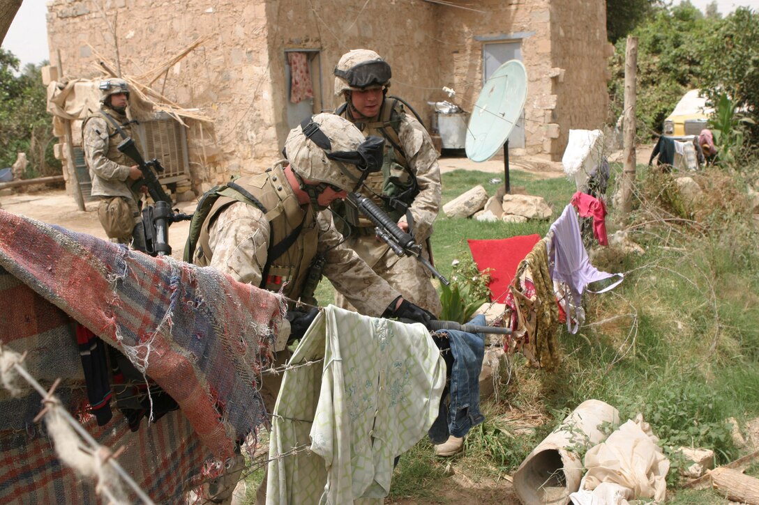 CAMP BLUE DIAMOND, AR RAMADI, Iraq - Members of the guard force here straddle a barbed wire fence while on patrol in the area outside the wall, Aug. 14.  U.S. Marine Corps photo by Sgt. Stephen D'Alessio (RELEASED)