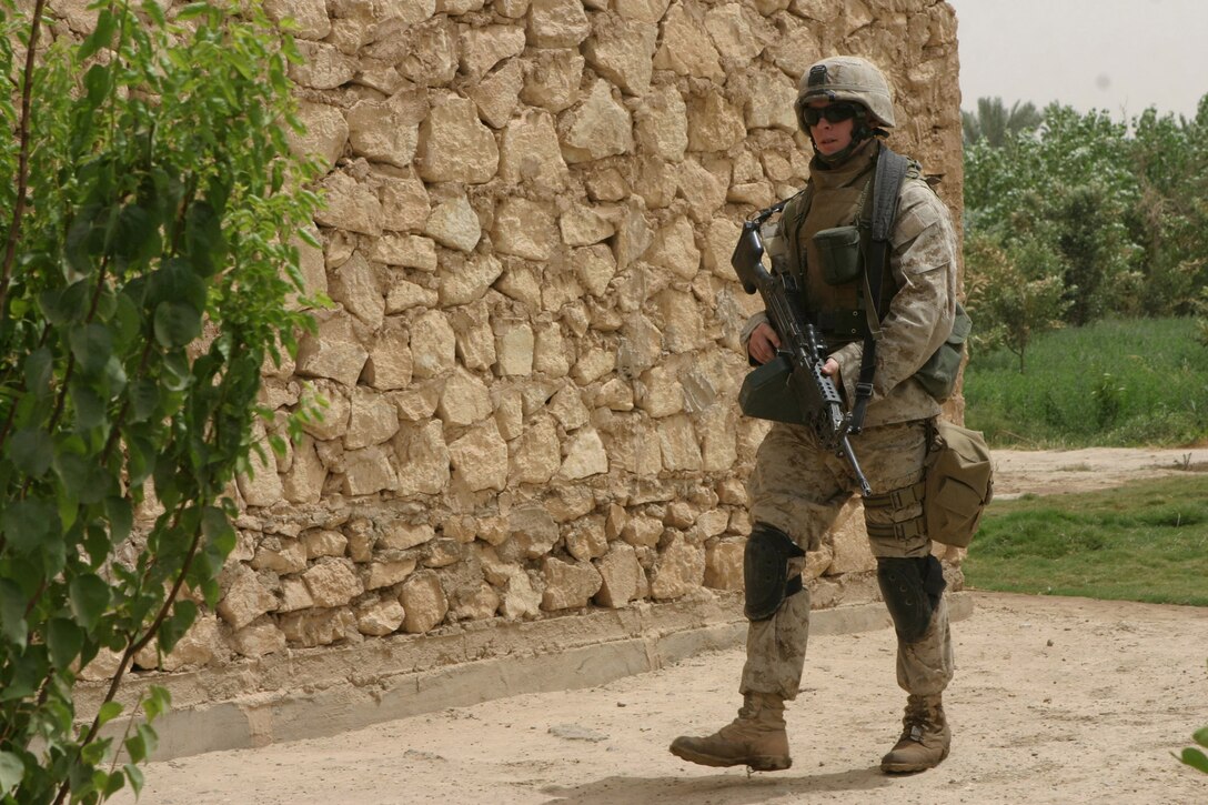 CAMP BLUE DIAMOND, AR RAMADI, Iraq - Corporal William Bryan Malin, a Squad Automatic Weapon machine gunner with the camp's guard force revels in his ability to be able to do something positive for the children here.  For the past six months, the 20-year-old Colorado Springs, Colo. native and his squad have been patrolling through the farm lands and villages that cushion the outside walls of the camp.  The children know who he is, because they usually get a little teddy bear when he passes through their field.  U.S. Marine Corps photo by Sgt. Stephen D'Alessio (RELEASED)