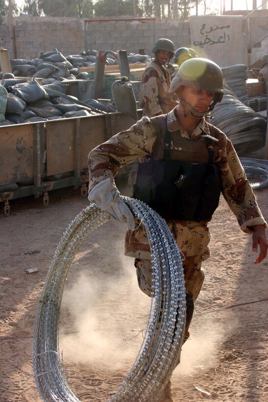 AR RAMADI, Iraq (Oct. 14, 2005) - A member of the Iraqi Security Force moves barbed wire to help prepare one of the election sites in preparation of the national constitutional referendum vote held Oct. 15. Photo by Cpl. Shane Suzuki