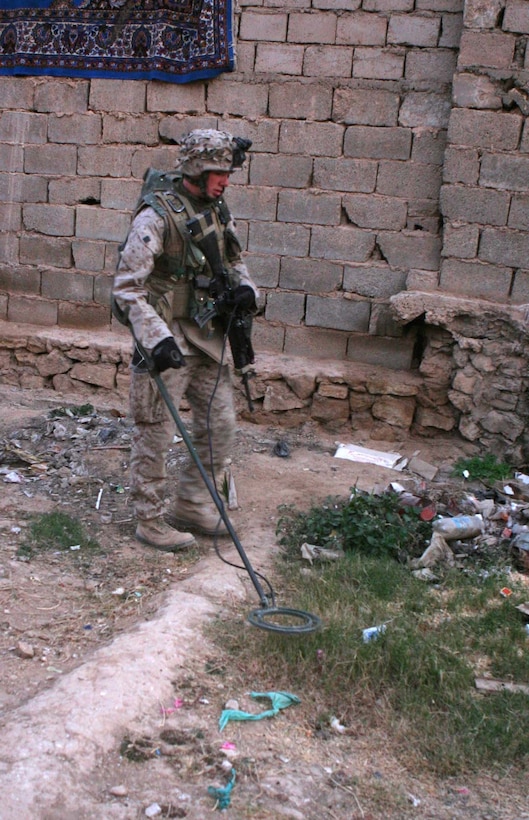 HAQLANIYAH, Iraq (Nov. 26, 2005)  - Oconomowoc, Wis. native, Lance Cpl. Darin J. Wittnebel, uses his PSS-12 metal detector to look for weapons caches in a courtyard here Nov. 26. Wittnebel, a rifleman with India Company, 3rd Battalion, 1st Marine Regiment, is one of a couple Marines in his company trained to operate the detector that helps make sure the town here is safe of weapons caches and improvised explosive devices. (Official Marine Corps photo by Cpl. Adam C. Schnell)