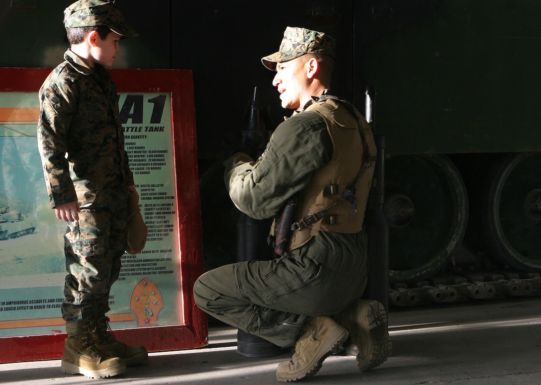 MARINE CORPS BASE CAMP LEJEUNE, N.C. (Dec. 14, 2005)- Sgt. Ricardo Fernandez Jr., a tank commander with 2nd Tank Battalion, 2nd Marine Division shows 6-year-old Brandon Rasnick rounds for a tank main gun. Brandon made a wish to train with Marines and save the world and that wish came true. (Official U.S. Marine Corps photo by Lance Cpl. Lucian Friel (RELEASED)