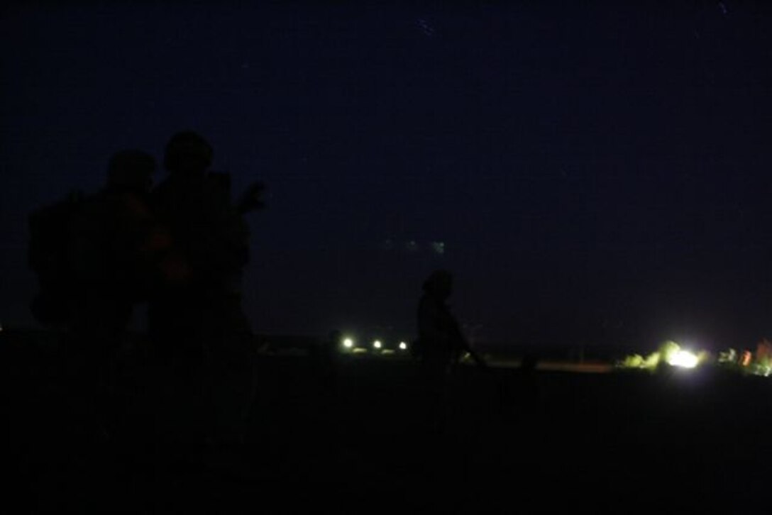 UBAYDI, Iraq ? The lights of Ubaydi are seen in the background as two Marines go over the attack plan and others provide watch during early morning hours, Nov. 14. The Marines, assigned to 3rd Platoon, Company E, 2nd Battalion, 1st Marine Regiment, participated in Operation Steel Curtain against insurgents here and within other border towns on the Lower Euphrates River Valley recently.