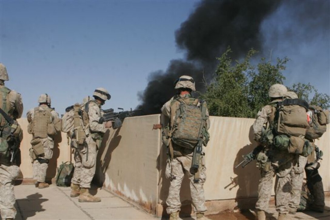 UBAYDI, Iraq ? Marines keep watch from a rooftop as smoke rises from house-to-house fighting, Nov. 14. The Marines assigned to 3rd Platoon, Company E, 2nd Battalion, 1st Marine Regiment, participated in Operation Steel Curtain against insurgents here and within other border towns on the Lower Euphrates River Valley recently.