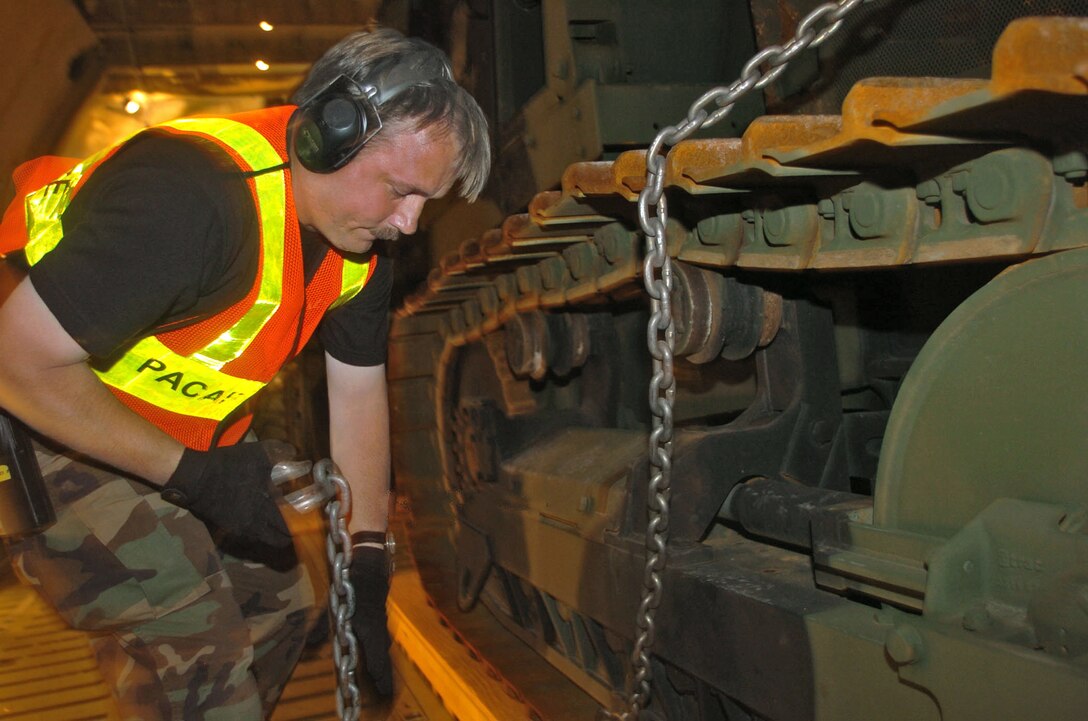 BANDANAIKE, Sri Lanka -- Master Sgt. Jeff Wisley unhooks tie-down chains so heavy equipment can be unloaded from a C-5 Galaxy aircraft.  The aircraft, assigned to the 60th Airlift Wing at Travis Air Force Base, Calif., landed at the international airport here supporting Operation Unified Assistance. U.S. servicemembers are helping bring relief supplies and equipment to various locations in Sri Lanka.  Sergeant Wisley is assigned to the Pacific Air Forces' tanker airlift control element at Yokota Air Base, Japan.  (U.S. Air Force photo by Master Sgt. Val Gempis)
