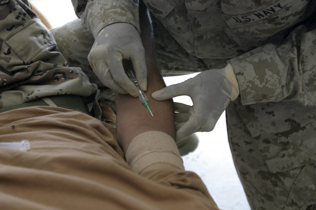 FALLUJAH, Iraq - Navy Petty Officer 2nd Class Phillip Jean-Gilles, a corpsman with 1st Battalion, 6th Marine Regiment, prepares to inject sodium chloride IV solution to a dehydrated Iraqi soldier at a training compound here May 11.  The 26-year-old Miami native and 1st Battalion, 6th Marine Regiment infantrymen tended to a dehydrated Iraqi soldier while teaching a five-day Iraqi combat leaders course.
