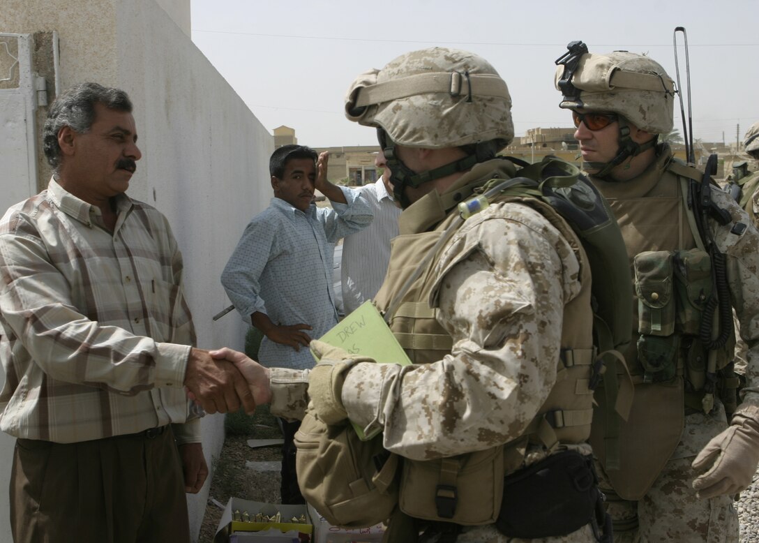 FALLUJAH, Iraq - Navy Lt. Brendon Drew, 1st Battalion, 6th Marine Regiment's surgeon, and Capt. Robert Hancock, Company B's, 1st Battalion, 6th Marine Regiment commander, shake hands with doctors outside a local clinic May 15.  American personnel worked alongside Iraqi Security Forces to speak with local doctors and clinic administrators to find out what supplies they needed, and how military personnel can help improve Iraq's medical system.