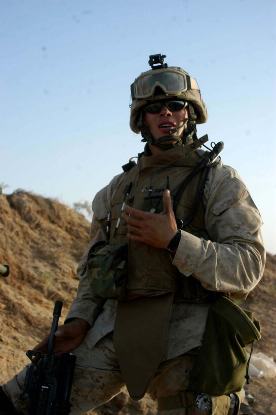 AR RAMADI, Iraq (Aug. 15, 2005) - Corporal Nicholas H. Cole, a combat engineer with 4th Platoon, Company A, 1st Combat Engineer Battalion, which is in direct support of 1st Battalion, 5th Marine Regiment, communicates with Marines in his platoon after having uncovered a weapons cache during a sweep through farmland on the outskirts of the city here Aug. 15. The 20-year-old from Weaverville, Calif., and his comrades found more than 300 artillery shells and approximately 2000 rounds of 7.62 mm ammunition during the mission. They consolidated the munitions into one whole and destroyed them with plastic explosives. Photo by: Cpl. Tom Sloan