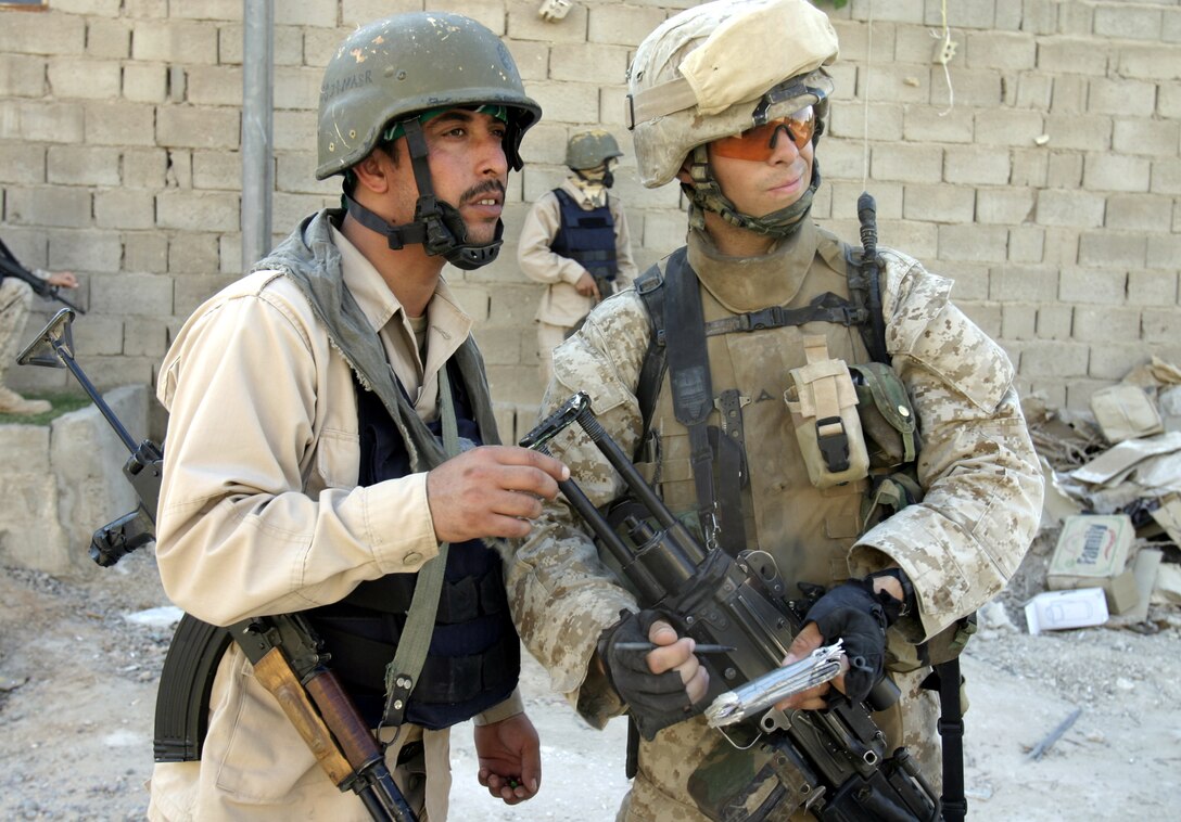 FALLUJAH, Iraq - Lance Cpl. Michael Hernandez, an infantryman with 4th Platoon, Company C, 1st Battalion, 6th Marine Regiment, and an Iraqi policeman determine which route to take next while patrolling the streets here Sept. 15 during Operation Hard Knock.  Iraqi Security Forces and Marine personnel detained three suspected insurgent supporters and confiscated one hand grenade during this three-hour-long house-to-house search mission.