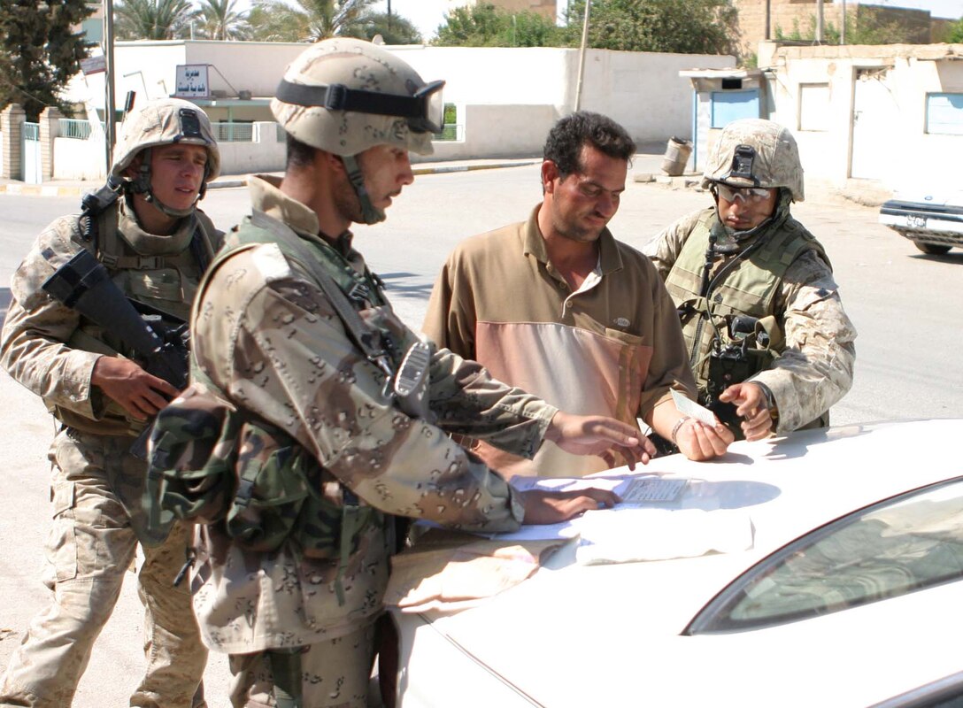 HIT, Iraq (Sept. 15, 2005)  - Lance Cpl. Randy B. Lake (Left), a radio operator for India Company, 3rd Battalion, 1st Marine Regiment and Sgt. Dominic A. Franco, a squad leader with the company work with an Iraqi Security Forces soldier while searching an Iraqi citizen here Sept. 15. The Marines and ISF soldiers perform patrols in the area daily to better stabilize the area. (Official Marine Corps photo by Cpl. Adam C. Schnell)