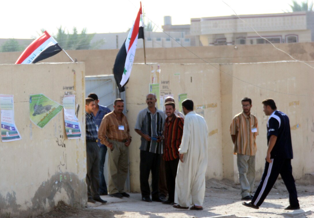 Iraqi citizens stand outside of a polling site in Fallujah after exercising their right to vote in elections held Oct. 15. The elections were held to vote on the referendum for Iraq?s newly drafted constitution. Marines from 2nd Battalion, 6th Marine Regiment worked jointly with the Iraqi Army to ensure area security. The battalion, along with the Iraqi Army, patrolled the area of 26 polling sites.