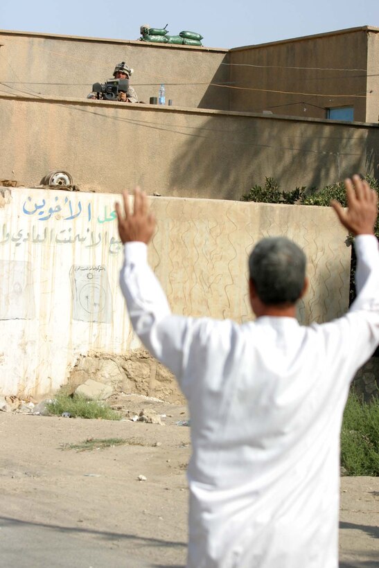 HADITHA, Iraq (Oct. 15, 2005)  - An Iraqi citizen lifts his arms to be checked for weapons or other objects by a Marine using an optic site before entering the polling site here Oct. 15. Lance Cpl. Steven R. Ybarra of Pomona, Calif. and other Marines with 3rd Battalion, 1st Marine Regiment, assisted Iraqi Security Forces providing security for these elections as more than 300 citizens cast their vote. (Official Marine Corps photo by Cpl. Adam C. Schnell)