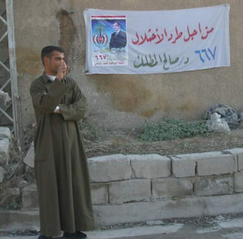 Standing by a sign for one of the candidates for parliament an Iraqi man displays an ink stained finger in the city of Fallujah Dec. 15. He was voting in a historic parliamentary election. After largely boycotting the election for the constitutional referendum in October, the largely Sunni population of Fallujah turned out in large crowds to vote.