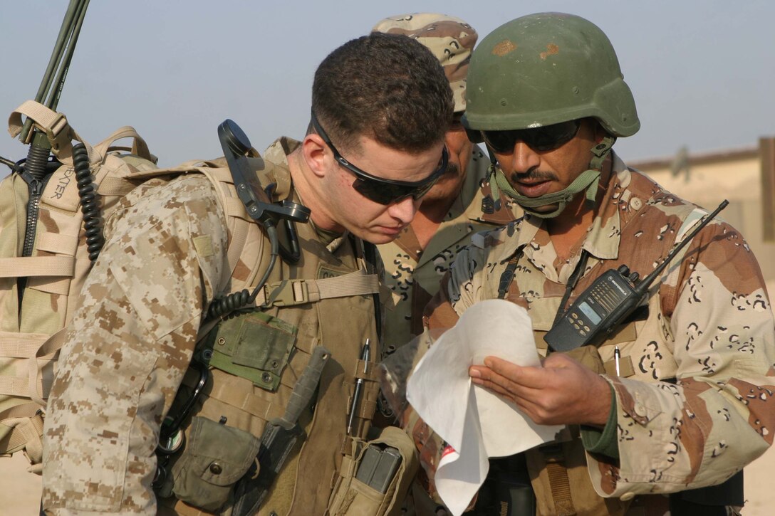 RAMADI, Iraq - Captain John M. Costello, a U.S. military advisor for 1st Battalion, 1st Brigade of the 7th Iraqi Army Division looks at a amp with an Iraqi soldier before patroling the streets of Tammim here Dec 15. The Iraqi soldiers accompanied by their U.S. military advisors provided a presence on the streets during Al Anbars provincial elections. Official U.S. Marine Corps photo by Sgt. Ryan S. Scranton